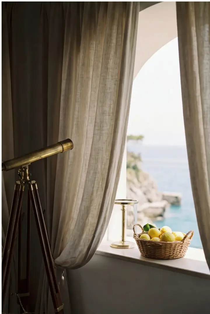 Linen curtains framing a yacht window above calm blue water